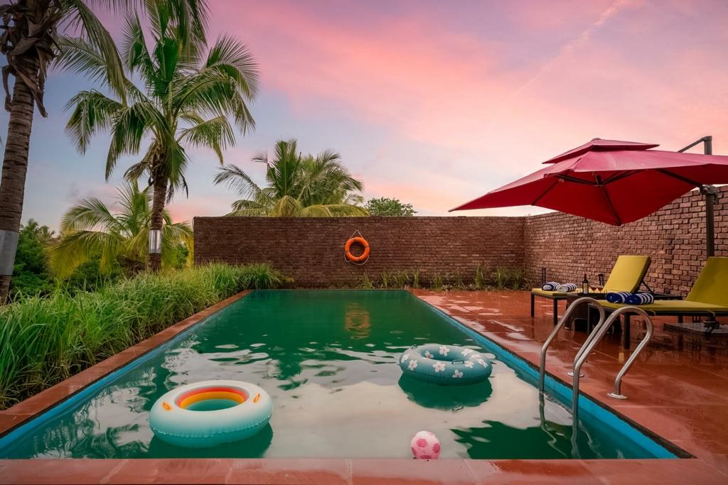 Contemporary villa with a spacious patio, infinity pool, and palm trees in the background.